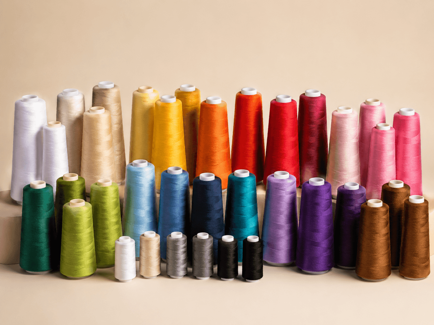 Thread cones arranged by colour family — neutrals, brights, darks and specialty shades